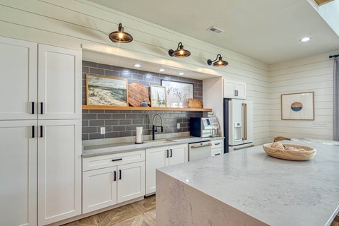 A kitchen with white cabinets and a marble countertop.