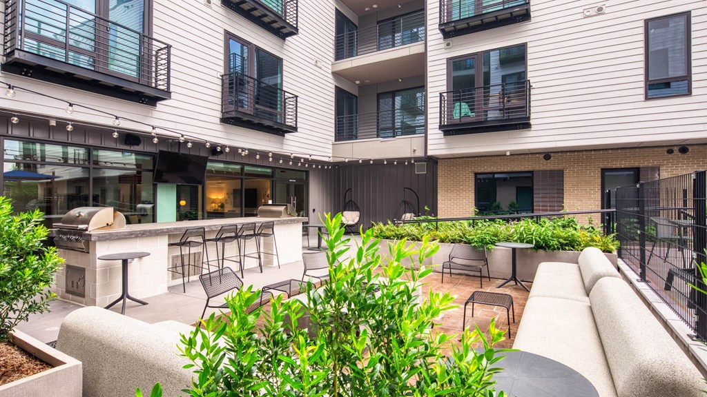 a patio with a bar and chairs in the middle of an apartment building