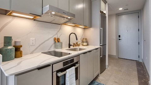 A kitchen with a white counter top and a stainless steel dishwasher.