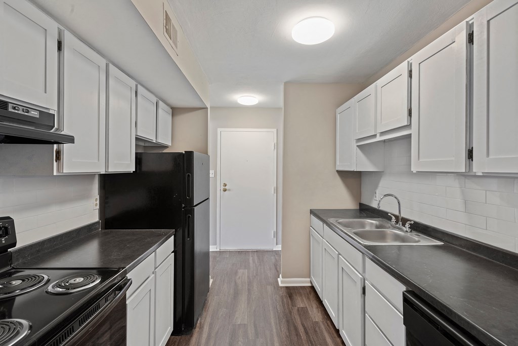 a kitchen with white cabinets and black countertops