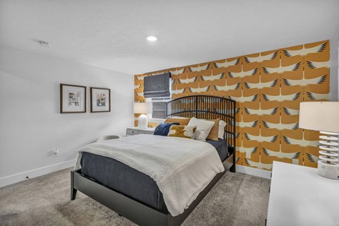 A bedroom with a bed, pillows, and pictures on the wall.