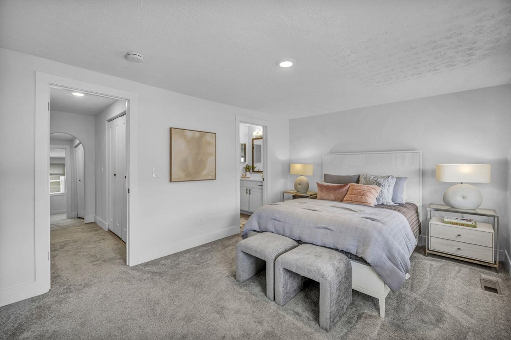 A bedroom with a bed, nightstand, and a grey tufted bench.
