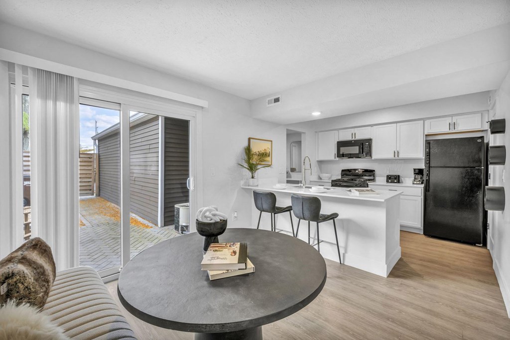 A modern kitchen with a black fridge and white cabinets.