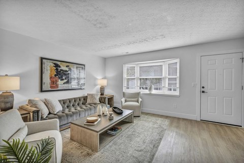 A living room with a grey couch, a coffee table, and a painting on the wall.