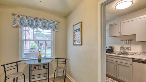 A kitchen area with a table and chairs is visible.