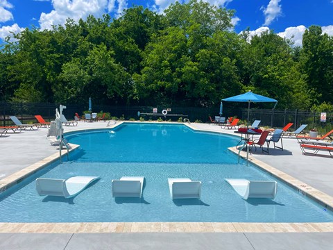 A pool with chairs and a blue umbrella.