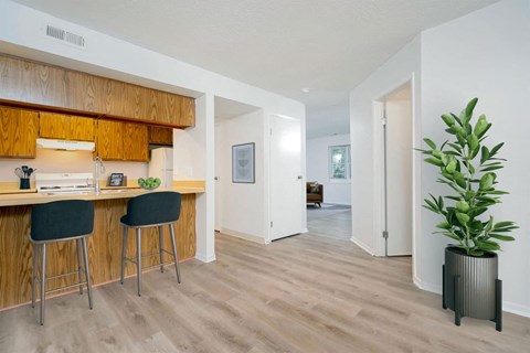 A kitchen with wooden cabinets and a bar area with two stools.