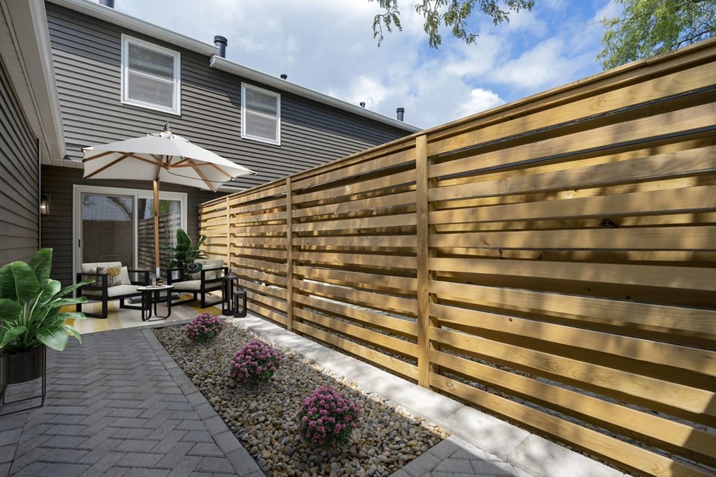 A patio with a wooden fence and a table with chairs.
