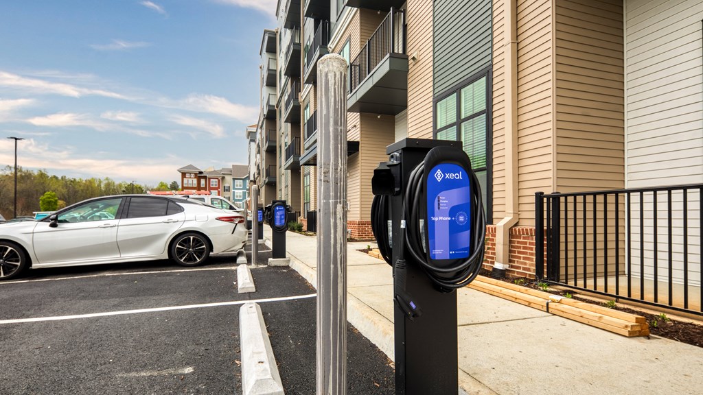 a parking meter with a white car parked in front of a building at Aura Stonebridge, Richmond, 23225
