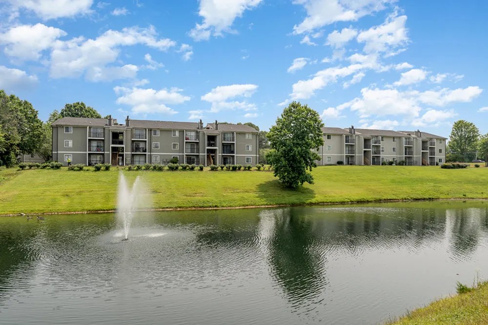 a fountain in the pond with an apartment building in the background at Village 1373, North Carolina