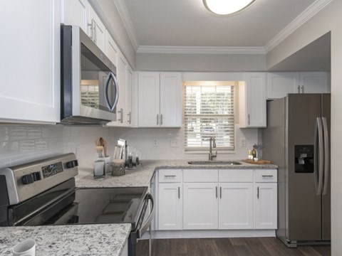 A kitchen with white cabinets and a stainless steel refrigerator.