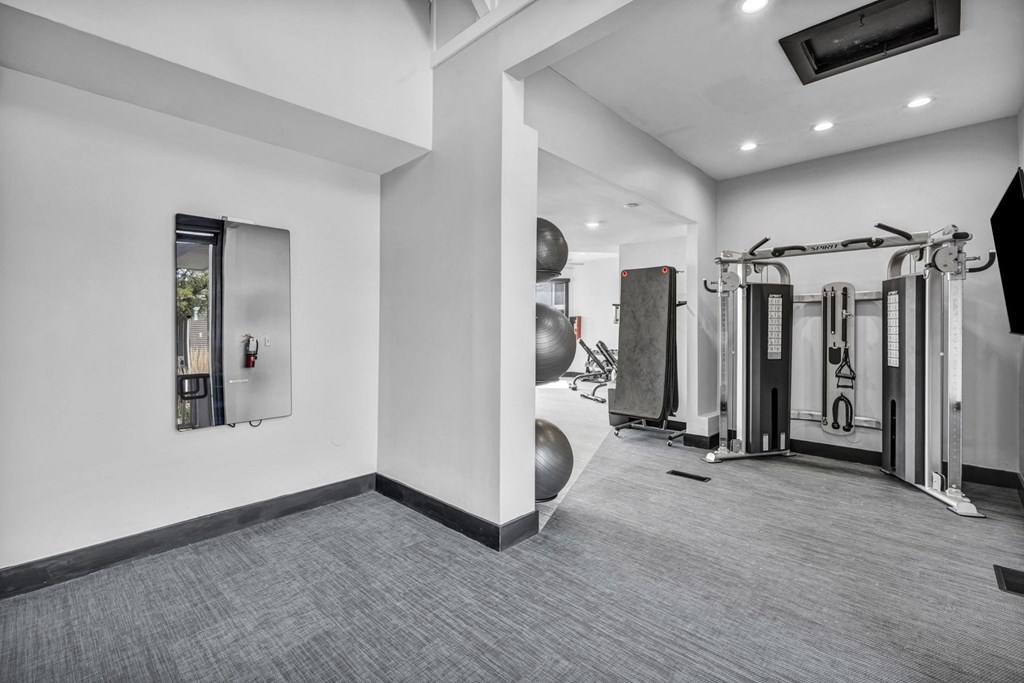 A gym with a variety of equipment including a treadmill, weights and a television.