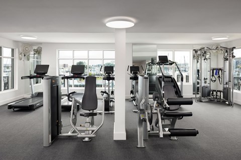 A gym with a variety of equipment including treadmills, weights, and exercise machines at The Port at East Beach Apartments and Marina in Virginia, 23518
