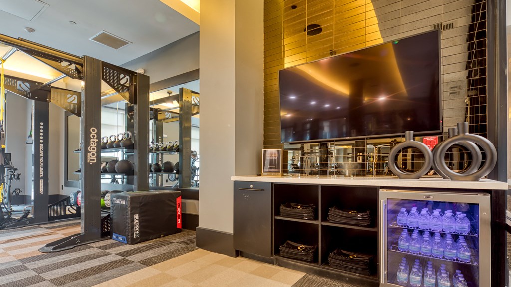 a fitness center with a large screen tv and a counter with water bottles at Aura Stonebridge, Virginia