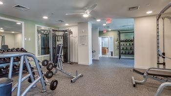 A gym with a variety of equipment including dumbbells, weight machines, and benches.