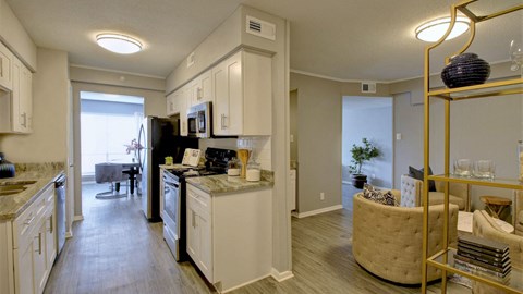 A kitchen with white cabinets and a black refrigerator.