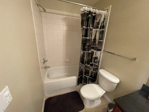 A white toilet sits next to a white bathtub in a bathroom.