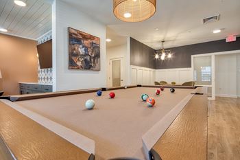 A pool table with balls set up for a game in a room with a painting on the wall.