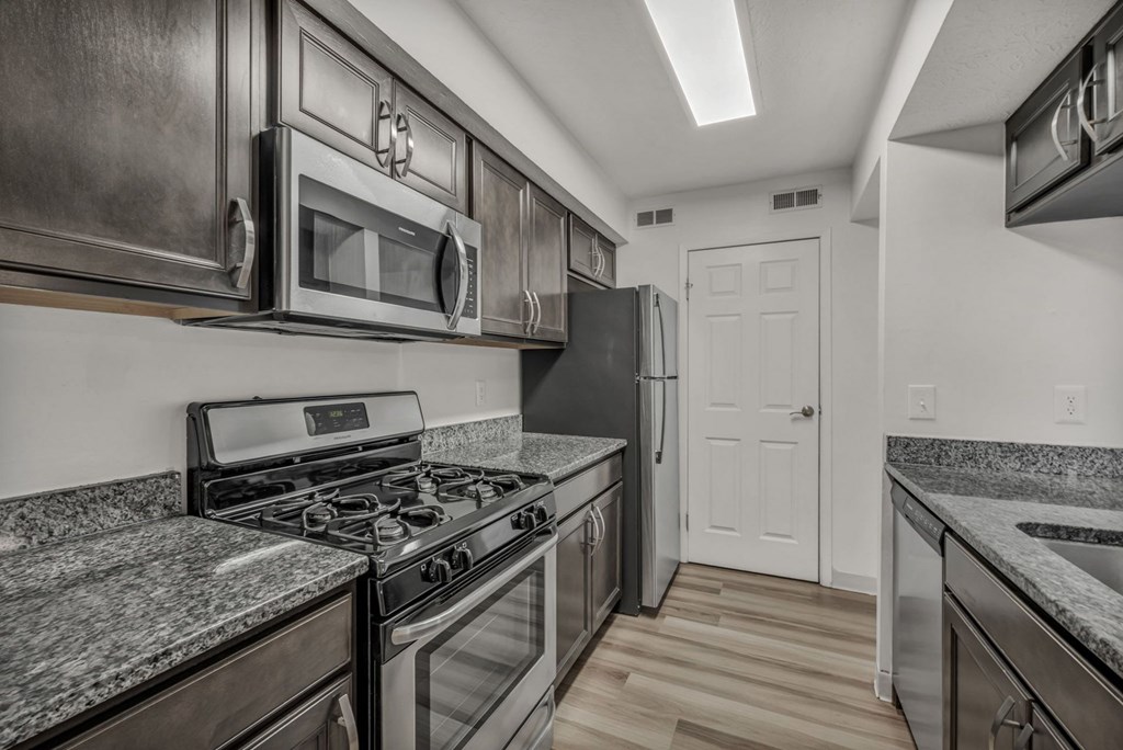 A kitchen with a stove, microwave, and refrigerator.