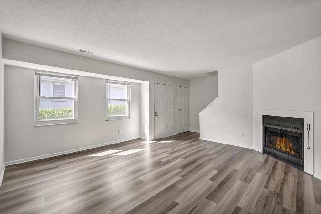 A room with a fireplace and wood flooring.