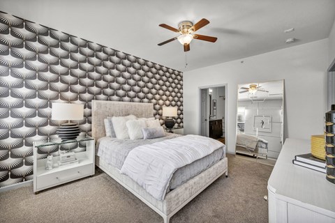A bedroom with a bed, dresser, and a ceiling fan.