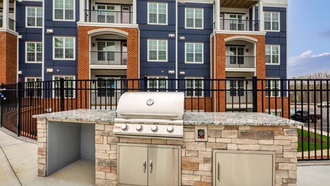 an outdoor kitchen with a stone island with a gas grill at The Bella at Westchester, Midlothian, 23113
