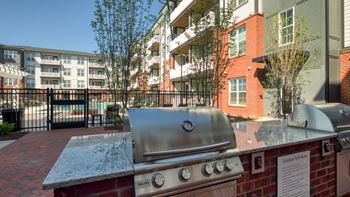 A BBQ grill is in front of a brick wall with a sign that says "Outdoor Barbecue".