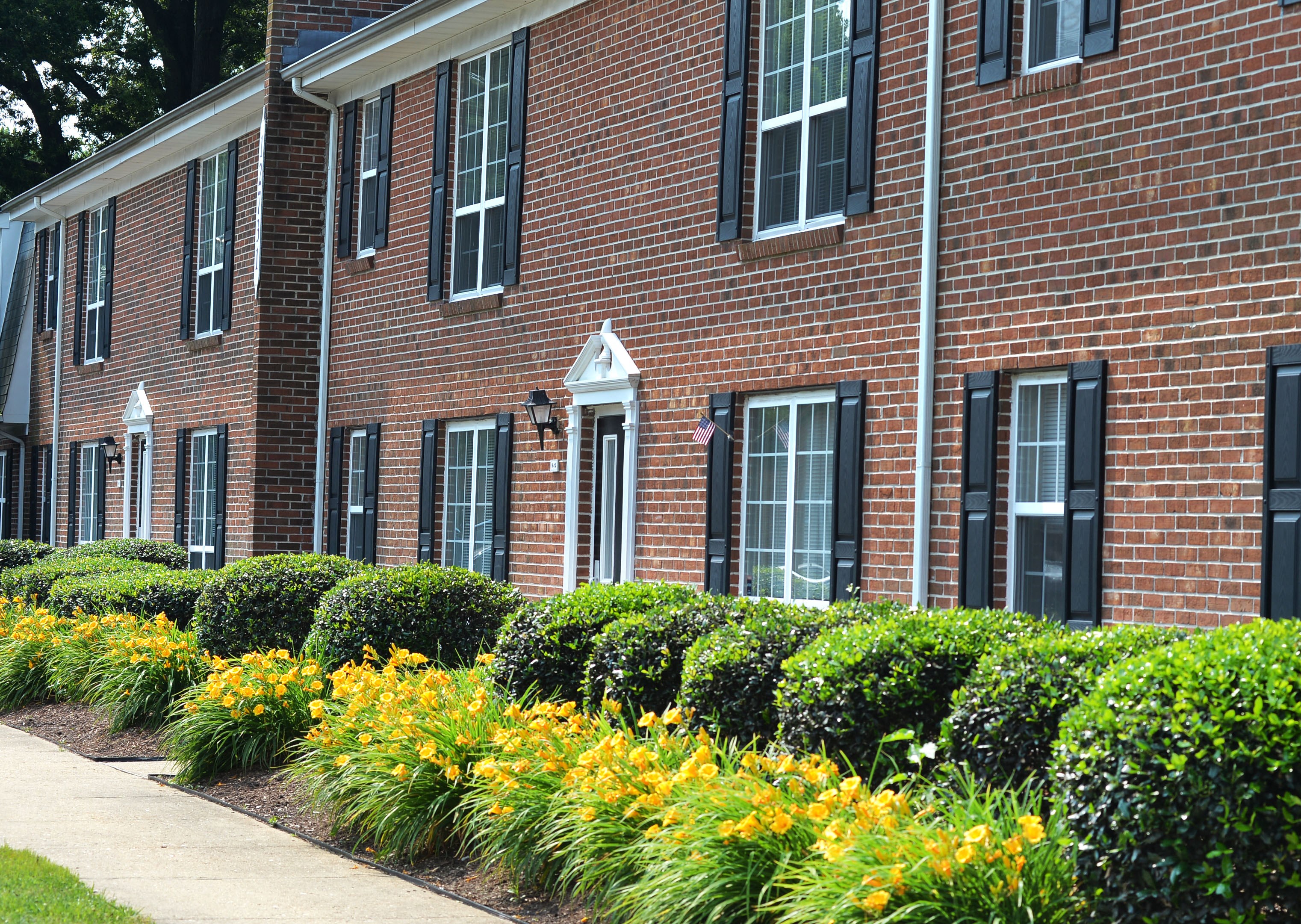 A red brick building with black shutters and a white door.