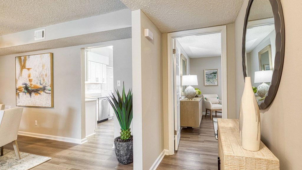 A living room with a painting on the wall and a potted plant on the floor.