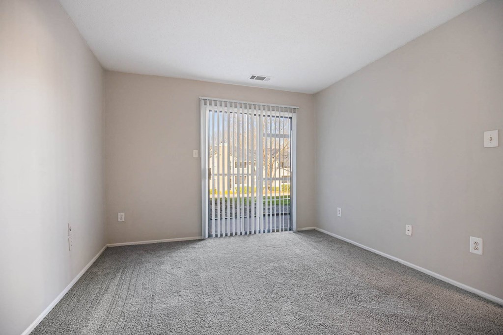 a spacious living room with a sliding glass door to a balcony