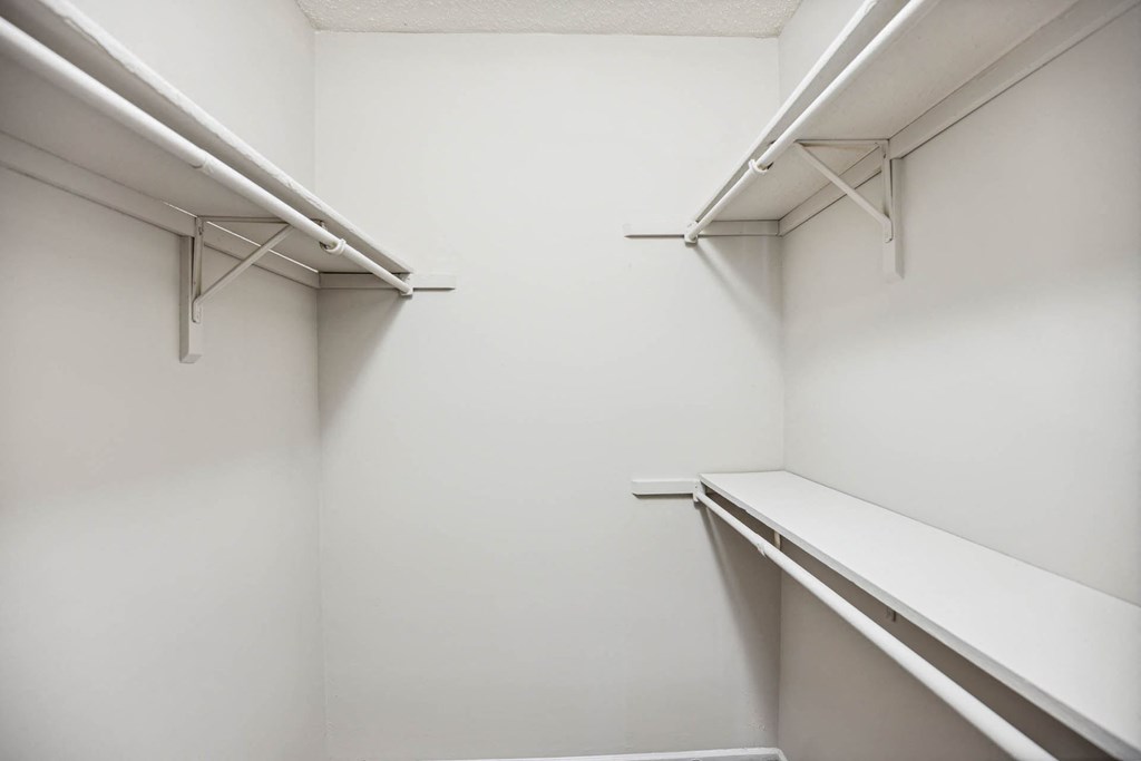 a walk in closet with white walls and a shelf