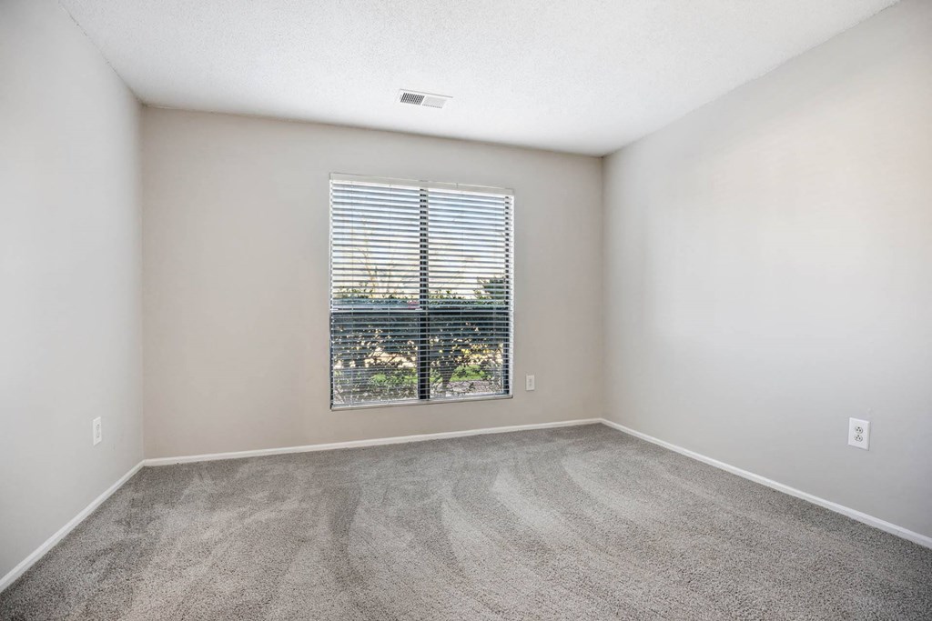 an empty living room with a window and carpeting