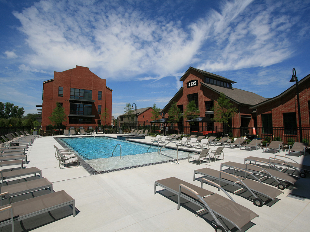 A pool with sun loungers and a building in the background.