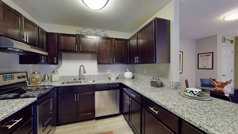 A kitchen with dark brown cabinets and granite countertops.