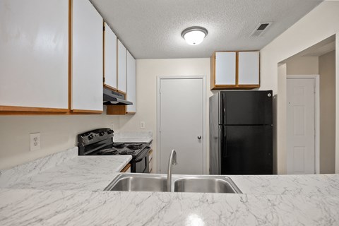 A kitchen with a black refrigerator and a marble countertop.