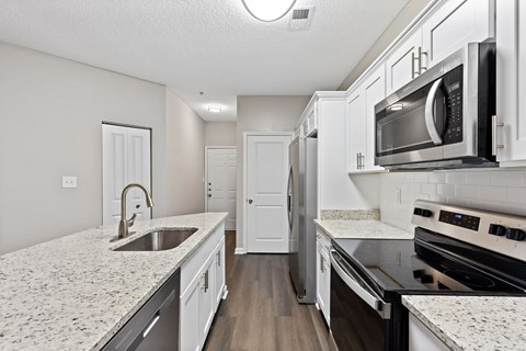 A kitchen with white cabinets and granite countertops.