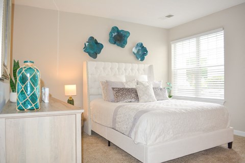 A white bedroom with a large bed and a white dresser.