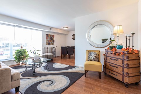 A living room with a yellow chair and a wooden chest of drawers.