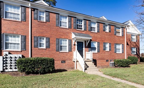 A red brick building with a white door and steps leading up to it.