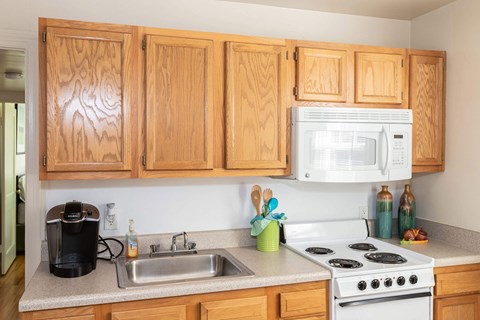 A kitchen with wooden cabinets and a white stove top oven.
