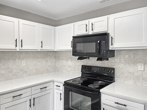 a kitchen with white cabinets and a black stove and a microwave