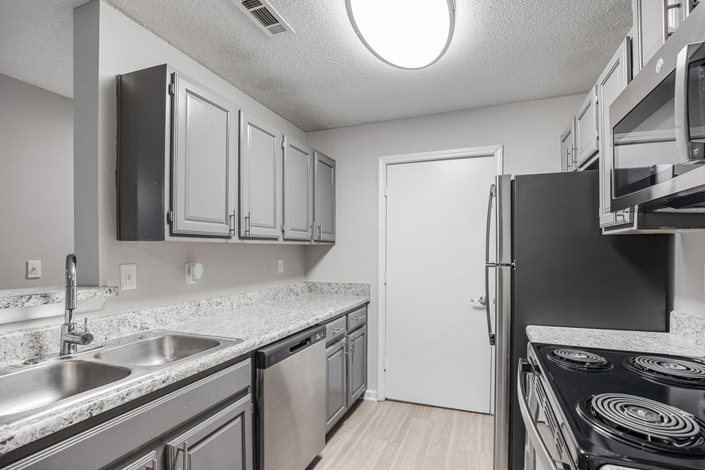 an empty kitchen with stainless steel appliances and granite counter tops at Midtown Crossing in Raleigh, NC