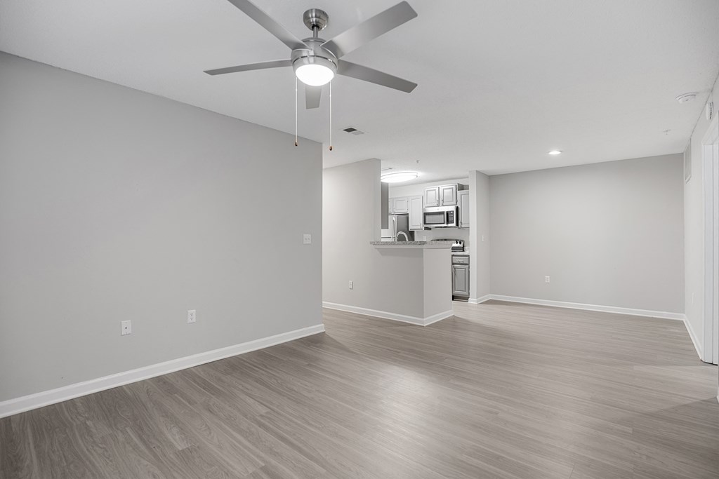 an empty living room with a ceiling fan and a kitchen at Midtown Crossing in Raleigh, NC