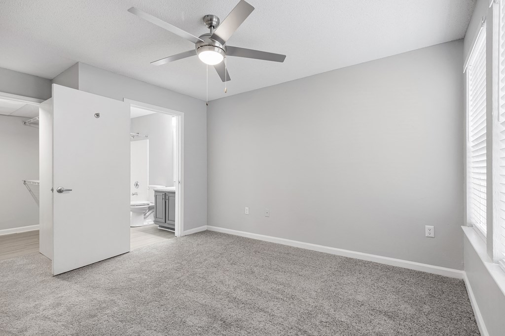 an empty living room with a ceiling fan and a door to a bathroom at Midtown Crossing in Raleigh, North Carolina