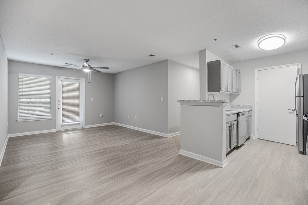 an empty living room and kitchen with a refrigerator and a sink at Midtown Crossing in Raleigh, 27609
