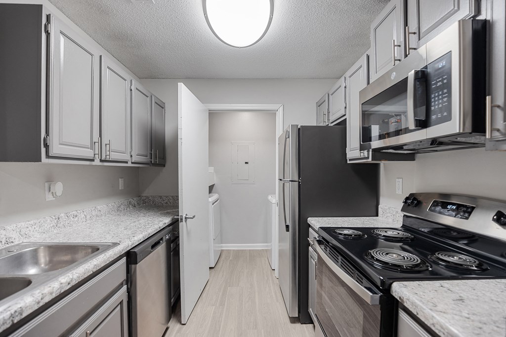 an empty kitchen with stainless steel appliances and white cabinets at Midtown Crossing in North Carolina 27609