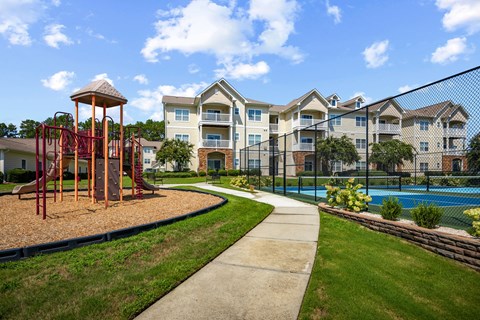 A playground with a swing set and a building in the background.