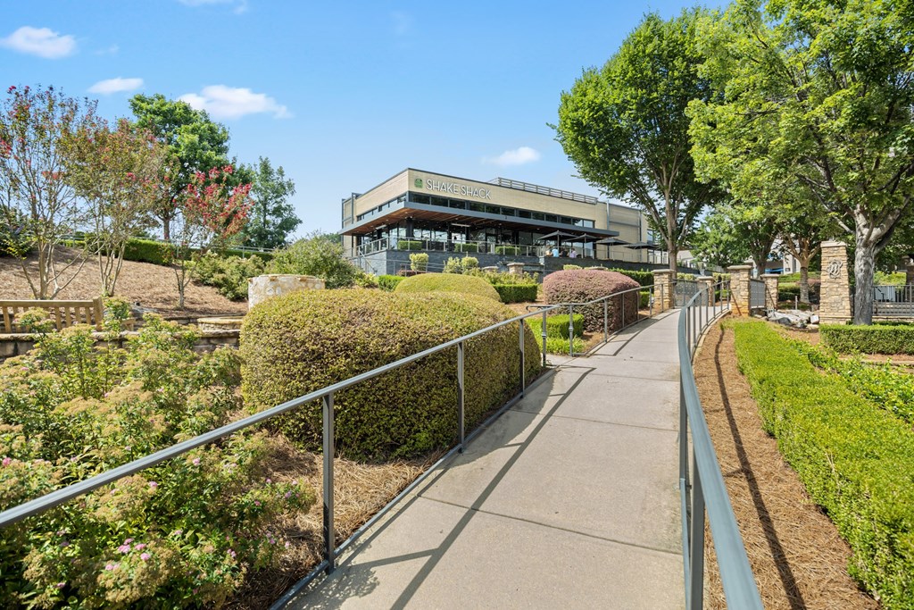 A pathway with a metal railing on the left side and a building in the background.