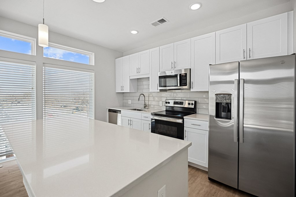 a large white kitchen with stainless steel appliances and white counter topsat Centro at Pine Nash, Wilson, NC, 27893