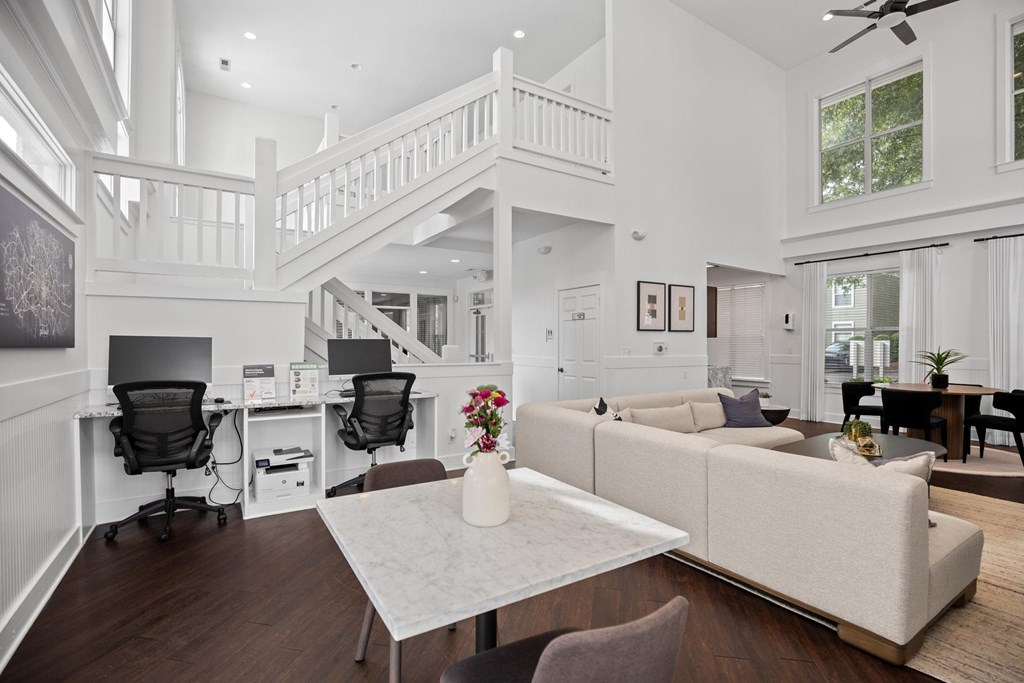 A white living room with a staircase and a dining area.